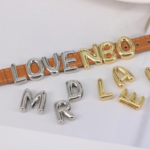 Puede incluir: Un conjunto de abalorios de letras plateadas y doradas, incluyendo las letras L, O, V, E, N, B, O, M, R, D, L, A y E. Los abalorios están en un estilo de fuente de burbuja y son perfectos para agregar un toque personalizado a las joyas.