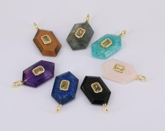 May include: A collection of gemstone pendants in various colors, including brown, gray, turquoise, purple, blue, black, and pink. Each pendant has a gold-colored bail and a central, rectangular, yellow-toned stone. The pendants are arranged on a white surface.