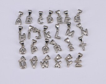 May include: A set of 26 silver alphabet letter charms. Each charm is a different letter of the alphabet, from A to Z. The charms are all the same size and shape, and they are all made of silver.