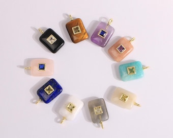 Puede incluir: Una colección de colgantes rectangulares de piedras preciosas en varios colores, incluyendo negro, marrón, morado, rosa, azul, blanco, gris y turquesa. Cada colgante presenta una piedra cuadrada engastada en un marco dorado y un lazo dorado para colgar.