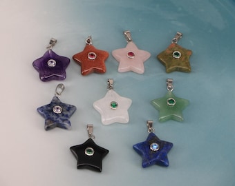 May include: A selection of star-shaped pendants in shades of purple, orange, pink, green, white, black, and blue. Each pendant features a silver-tone bail and a gemstone centre. The pendants are presented on a light blue surface.