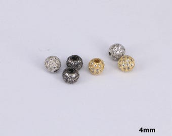 Puede incluir: Una colección de pequeñas cuentas redondas, cada una de aproximadamente 4 mm de diámetro. Las cuentas son de varios colores, incluyendo plata, negro y oro, y están incrustadas con pequeñas piedras brillantes. Estas cuentas son adecuadas para la fabricación de joyas.