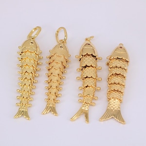 May include: Four gold-colored fish pendants with detailed scale and fin designs. Each pendant has a loop at the top for hanging. The fish vary slightly in tail shape and overall design, all with a shiny, metallic finish.