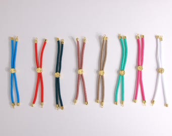 Könnte beinhalten: Eine Sammlung farbenfroher Seilketten mit goldfarbenen Akzenten. Die Halsketten sind in verschiedenen Farben erhältlich, darunter Blau, Rot, Grün, Rosa und Weiß. Jede Halskette hat einen kreisförmigen, goldfarbenen Anhänger und goldfarbene Endkappen.