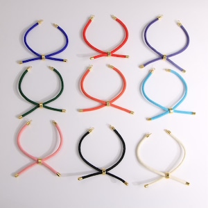 Puede incluir: Nueve collares de cuerda coloridos en varios colores, incluyendo azul, rojo, morado, verde, naranja, celeste, rosa, negro y crema. Cada collar presenta un cierre dorado y un conector central dorado.