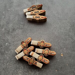 Könnte beinhalten: Eine Sammlung von neun Zigarrenringen mit goldenen, roten und schwarzen dekorativen Elementen. Drei Ringe sind oben horizontal gestapelt, während sechs weitere unten in einer Gruppe angeordnet sind. Jeder Ring zeigt den Text PATRON oder SELECT.