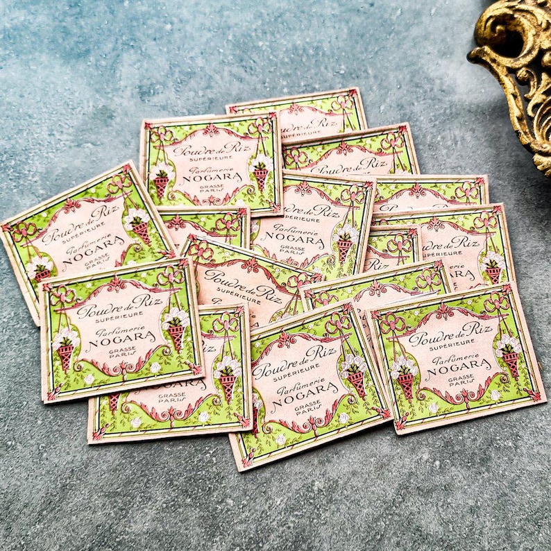 May include: A pile of vintage, green and pink, rectangular, decorative boxes with the text "Poudre de Riz Superieure Parfumerie Nogara Grasse Paris" on each box.