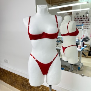 Peut inclure: Ensemble de lingerie rouge pr&eacute;sent&eacute; sur un mannequin blanc. L'ensemble comprend un soutien-gorge avec armatures et bretelles r&eacute;glables, et un string assorti. La lingerie est en mati&egrave;re douce et velout&eacute;e.