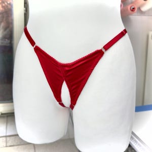May include: A red satin thong with a low-rise design. The lingerie features a delicate, scalloped trim along the edges and adjustable straps. The open design adds a touch of allure.
