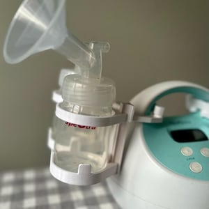 May include: A white and teal electric breast pump with a clear bottle and a funnel attached. The pump has a digital display with the word "cycle" on it.