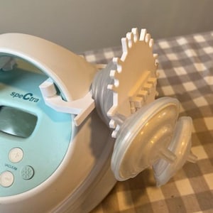 May include: A white and blue electric breast pump with a digital display and a white control knob labelled "vacuum". The pump has two white flanges attached to it.