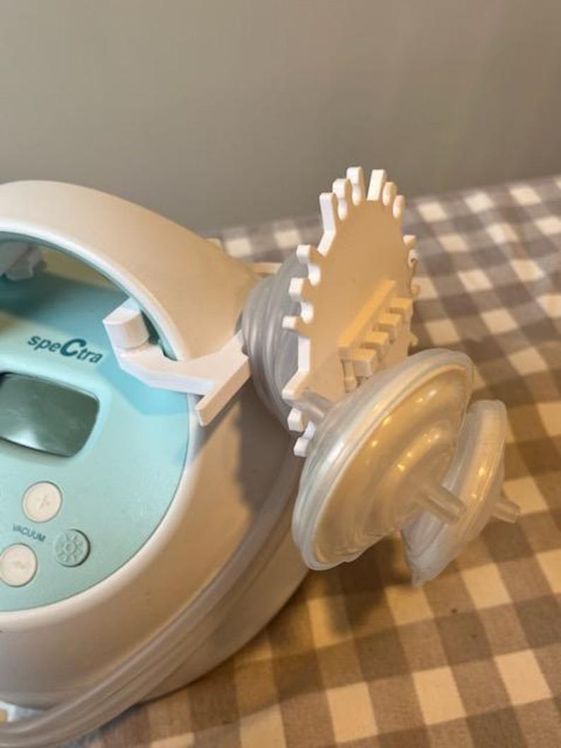 May include: A white and blue electric breast pump with a digital display and a white control knob labelled "vacuum". The pump has two white flanges attached to it.