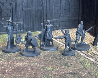 May include: Five gray plastic miniature figurines of fantasy characters. The figures are standing on a gray and brown surface. The figures include a witch, a warrior, a dwarf, a sorceress, and an elf.