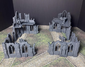 May include: Gray miniature gothic ruins with arched windows and battlements. The set includes several modular pieces, with small figurines placed on top, creating a detailed tabletop gaming environment.