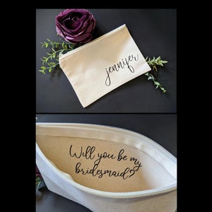 May include: A white canvas zippered pouch with the name "Jennifer" printed on the front. The pouch is open to reveal the text "Will you be my bridesmaid?" printed on the inside.