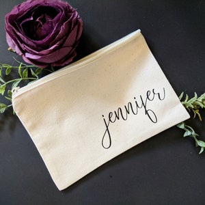 May include: A white canvas zippered pouch with the name "jennifer" written in black cursive script.
