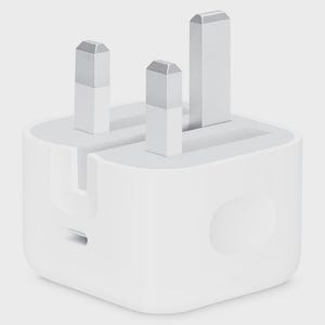 Puede incluir: Un adaptador de corriente blanco con tres clavijas con puntas plateadas. El adaptador tiene un cuerpo rectangular con bordes redondeados y un pequeño puerto en el lateral. El diseño es limpio y moderno.