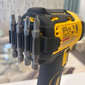 May include: A yellow and black cordless impact driver with a set of silver drill bits attached. The driver has the model number DCF787 and a warning label. The handle is black and the body is yellow.