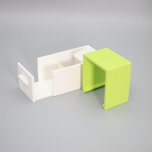 K&ouml;nnte beinhalten: Ein modernes Schreibtisch-Organizer-Set in Wei&szlig; und Limettengr&uuml;n. Der wei&szlig;e Organizer hat F&auml;cher und eine ausziehbare Schublade. Das limettengr&uuml;ne Teil ist ein kleiner, offen-seitiger W&uuml;rfel. Das Set besteht aus einem glatten, matten Material.