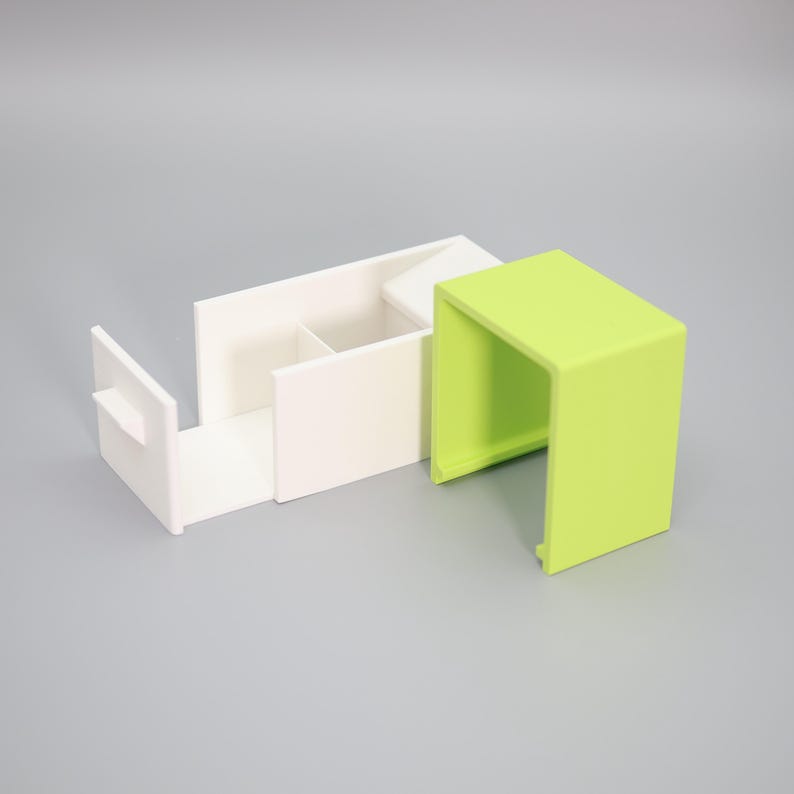 K&ouml;nnte beinhalten: Ein modernes Schreibtisch-Organizer-Set in Wei&szlig; und Limettengr&uuml;n. Der wei&szlig;e Organizer hat F&auml;cher und eine ausziehbare Schublade. Das limettengr&uuml;ne Teil ist ein kleiner, offen-seitiger W&uuml;rfel. Das Set besteht aus einem glatten, matten Material.