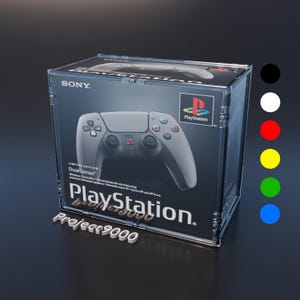 Può includere: Una scatola di plastica trasparente che contiene un controller wireless PlayStation DualSense bianco e nero. La scatola ha il logo PlayStation e il testo "Project 9000".
