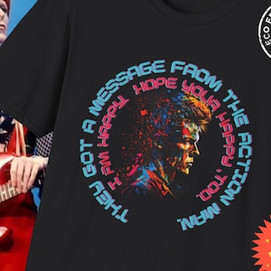 May include: Black t-shirt with a colorful graphic of a person's face surrounded by a circle of text that reads "They got a message from the action man I'm happy. Hope your happy too."