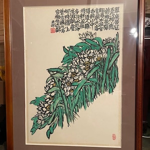 May include: An artistic framed print featuring a watercolor painting of white flowers with yellow centers and green leaves. The artwork includes Chinese calligraphy in black ink and is set within a brown wooden frame.