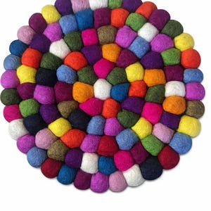 Puede incluir: Un salvamanteles redondo de fieltro compuesto por numerosas bolitas de fieltro pequeñas y apretadas. El salvamanteles presenta una vibrante gama de colores, incluyendo rojo, naranja, amarillo, verde, azul, morado y blanco, creando una superficie texturizada y atractiva.