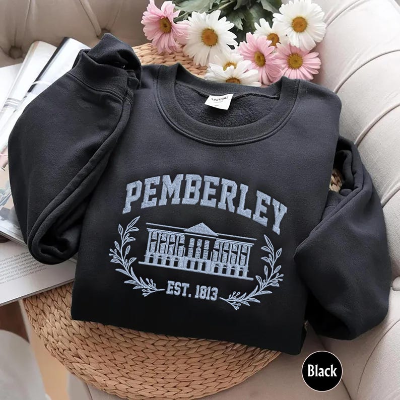 May include: Black sweatshirt with a white embroidered design that says "Pemberley Est. 1813" with a building and floral accents.