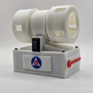 Puede incluir: Un dispositivo blanco impreso en 3D con un diseño cilíndrico, con un interruptor de encendido/apagado negro y un emblema rojo. El dispositivo tiene una base rectangular y una serie de aberturas circulares y rectangulares.