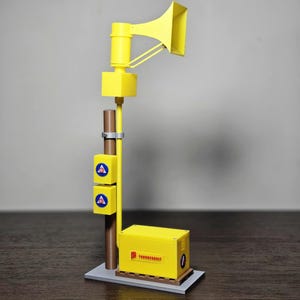 Peut inclure: Maquette jaune d'une sirène de sécurité publique. Le modèle comprend une base rectangulaire, un boîtier jaune avec du texte, deux boîtes jaunes avec des symboles bleus et blancs, un poteau marron et un haut-parleur jaune en forme de corne.