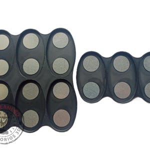 May include: Two black plastic trays with multiple circular depressions. The trays are designed to hold small round objects, such as paint pots or other small containers. The trays are made of a durable plastic and are easy to clean.