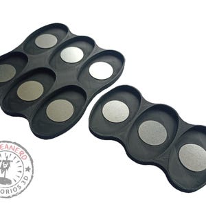 May include: Two black plastic trays with circular indentations for holding small round objects. The trays are designed for organizing and storing small items.