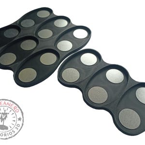 May include: Two black plastic trays with circular indentations for holding small objects. The trays are designed to hold paint pots or other small items.