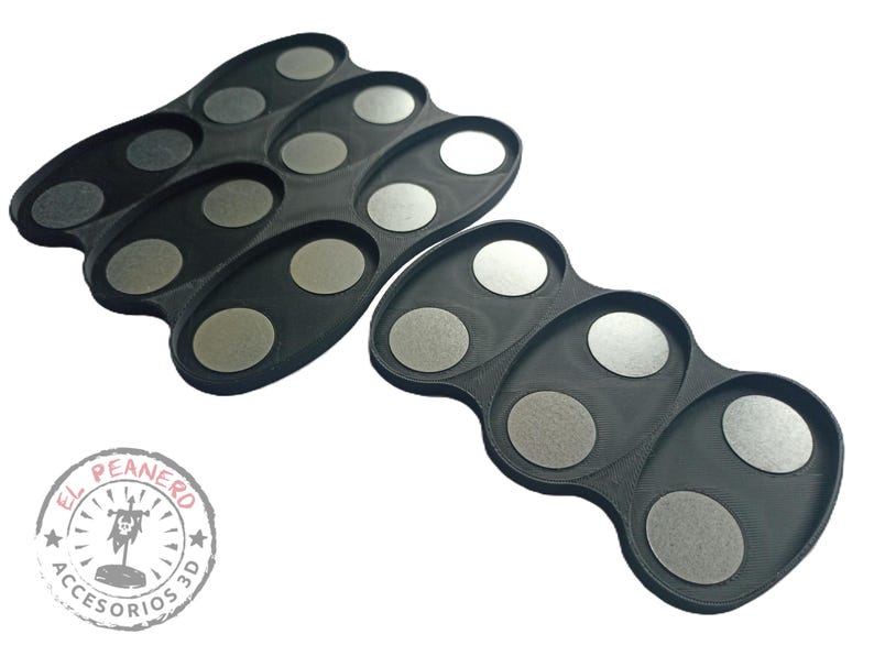 May include: Two black plastic trays with circular indentations for holding small objects. The trays are designed to hold paint pots or other small items.