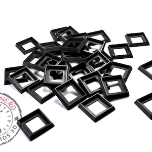Pode incluir: Um monte de molduras quadradas de plástico preto. As molduras são todas do mesmo tamanho e estão empilhadas umas sobre as outras.