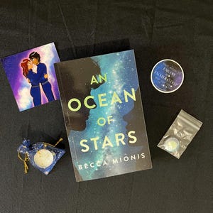 May include: A collection of items including a book titled "An Ocean of Stars" by Becca Mionis, a sticker, a small bag, and a card with a couple embracing. The book cover features a silhouette and a starry background. The sticker reads "That which is far off exceeding deep".