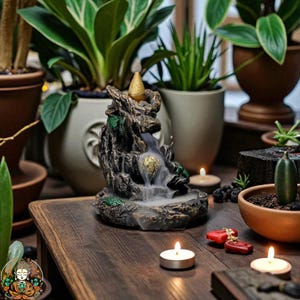 Puede incluir: Una cascada de incienso decorativa con un diseño texturizado detallado. La cascada es marrón y verde, con un cono dorado en la parte superior. La imagen incluye velas encendidas, plantas y una superficie de madera.