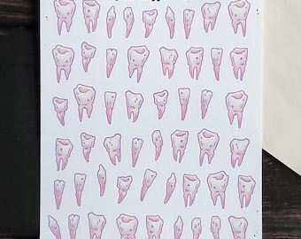 May include: A sheet of pastel pink tooth stickers with the text "Pastel Teeth" and "PAPER HAUNT." The sheet is white with a black border and includes 36 stickers.