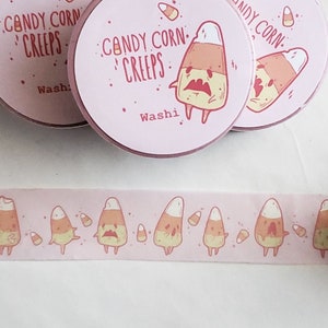 May include: Three rolls of pink washi tape with a repeating pattern of cartoon candy corn characters. The tape is labeled "Candy Corn Creeps" and "Washi".