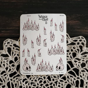 May include: A sheet of stickers featuring a variety of white candles with pink flames. The stickers are on a white background and include two skull designs with the text "Vampire's Crypt".