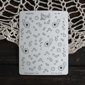 May include: A sheet of white sticker paper with a black and white design of bubbles with skulls inside. The sheet is titled "Bubbles" and has the text "Mermaid Lane" and "Art by Stag." at the bottom.