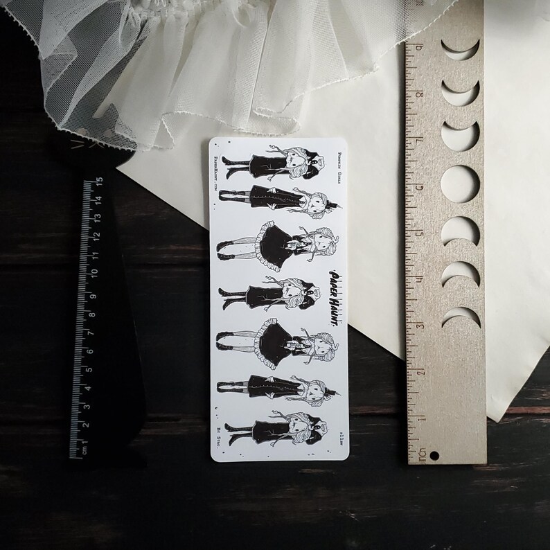 May include: A sheet of black and white stickers featuring illustrations of girls wearing dresses and hats. The stickers are labeled "Paper Haunt".
