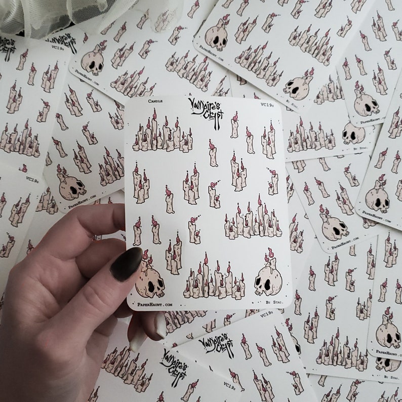 May include: A sheet of stickers featuring a variety of illustrations of candles and skulls. The stickers are white with black outlines and pink flames. The text "YANDIRA'S CRAFT" is printed on the sheet. The text "VC134" is printed on the sheet.