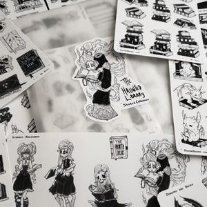 May include: A set of black and white stickers featuring illustrations of a haunted library, dragons, and books. The stickers are part of a sticker collection called "The Haunted Library".