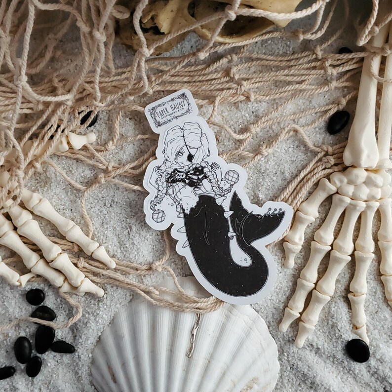 Gothic pirate mermaid sticker by artist White stag for Paper Haunt Stationery & Co on sand with a fishing net.