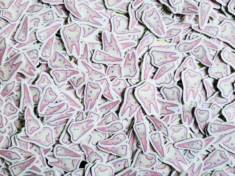May include: A large collection of pink tooth stickers. The stickers are all different shapes and sizes, and some have a sparkly finish.