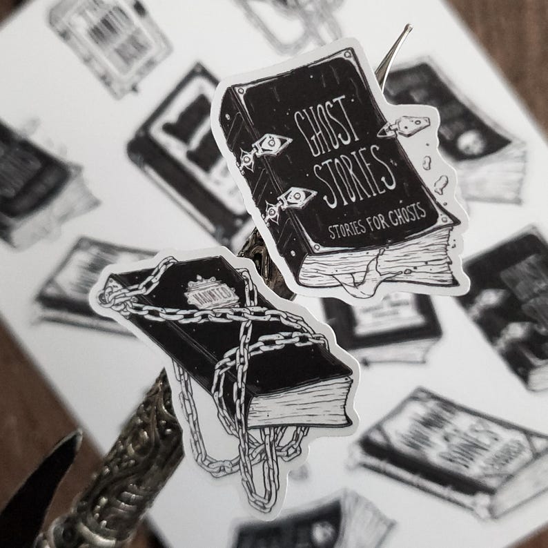 May include: Two black and white illustrated stickers of books. One book is titled "Ghost Stories" with the subtitle "Stories for Ghosts". The other book is chained shut and has the word "Haunted" on the cover.