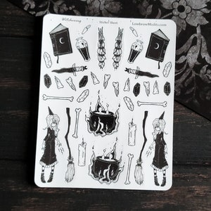 May include: A black and white sticker sheet with a witching theme. The sheet includes a witch, a cauldron, a book, a dagger, bones, crystals, candles, and a broom. The text "Witching" and "Sticker Sheet" are at the top of the sheet. The text "LowbrowMisfits.com" is at the top right of the sheet.