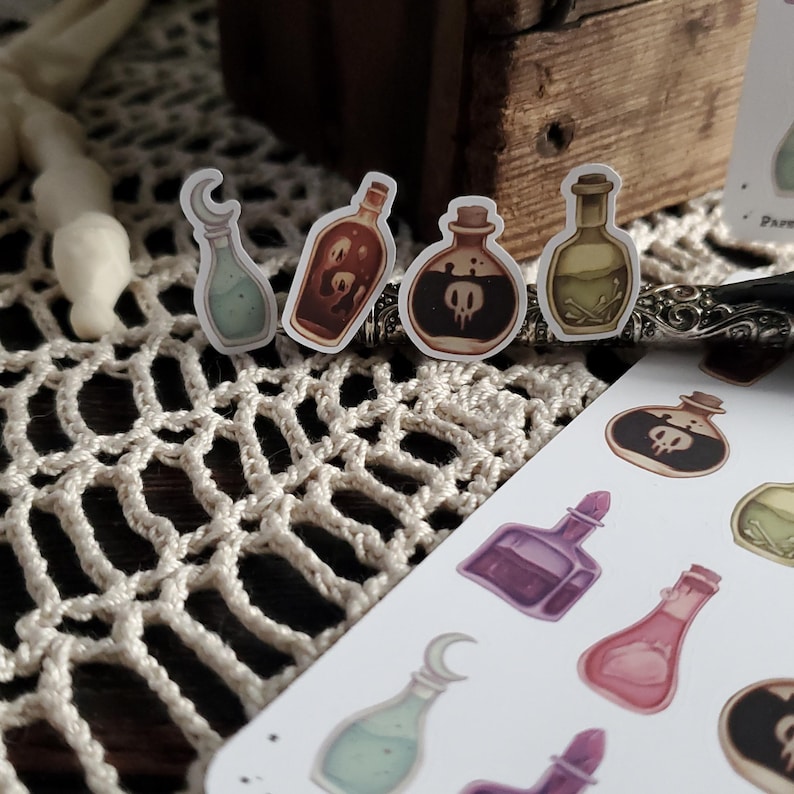 May include: A sheet of stickers featuring various potion bottles with different colored liquids and designs. The bottles have a whimsical, gothic aesthetic.